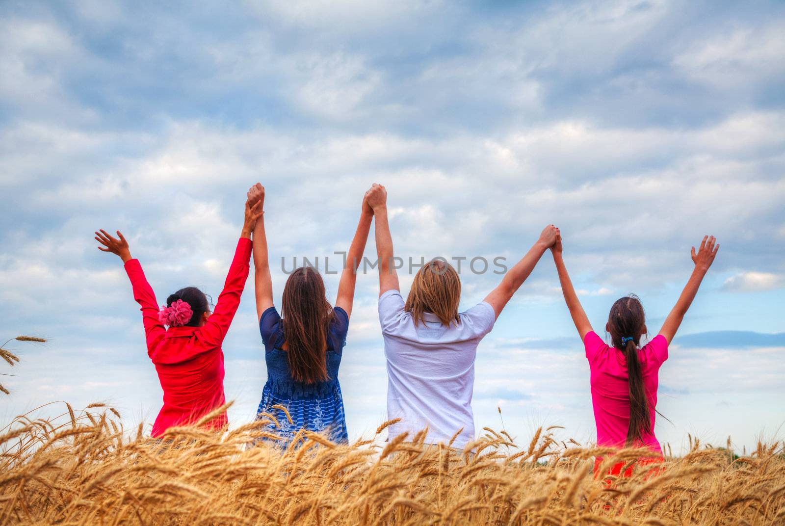 Four young people staying with raised hands by AndreyKr
