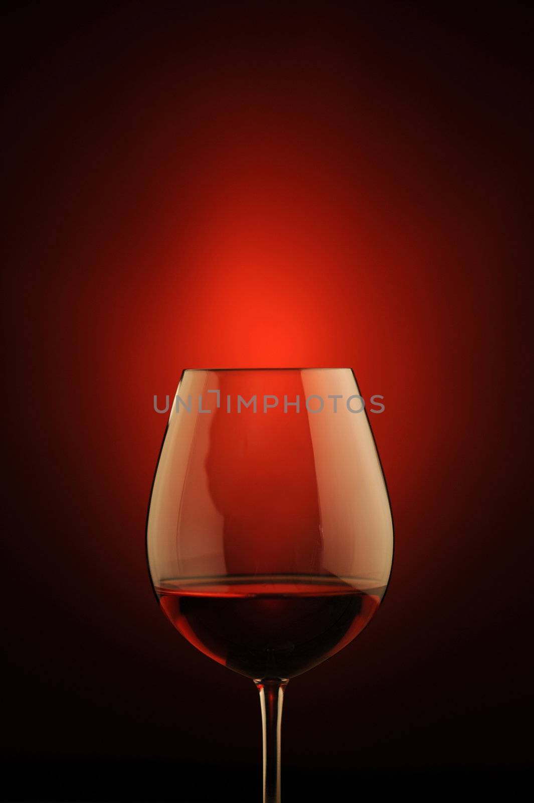 red wine glass , red light on background by stokkete