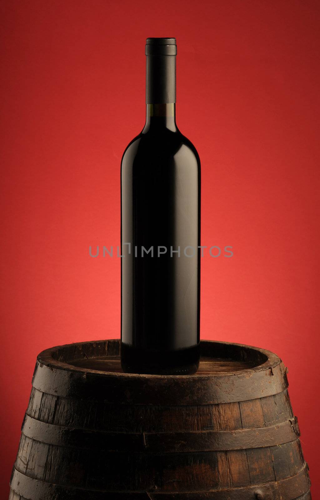 red wine bottle on wooden barrel