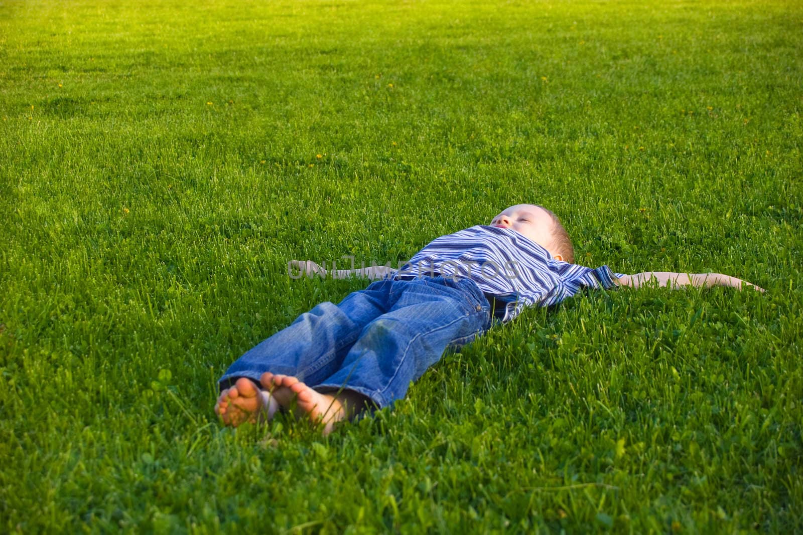 The four-year boy lies on a grass 