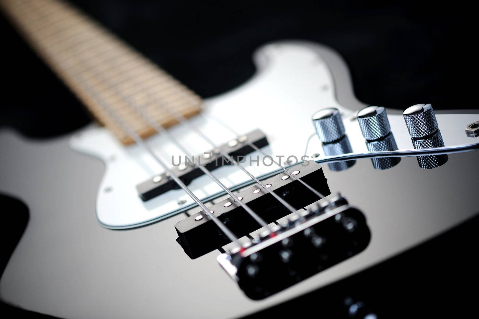 close up of a black electric bass glossy on dark background