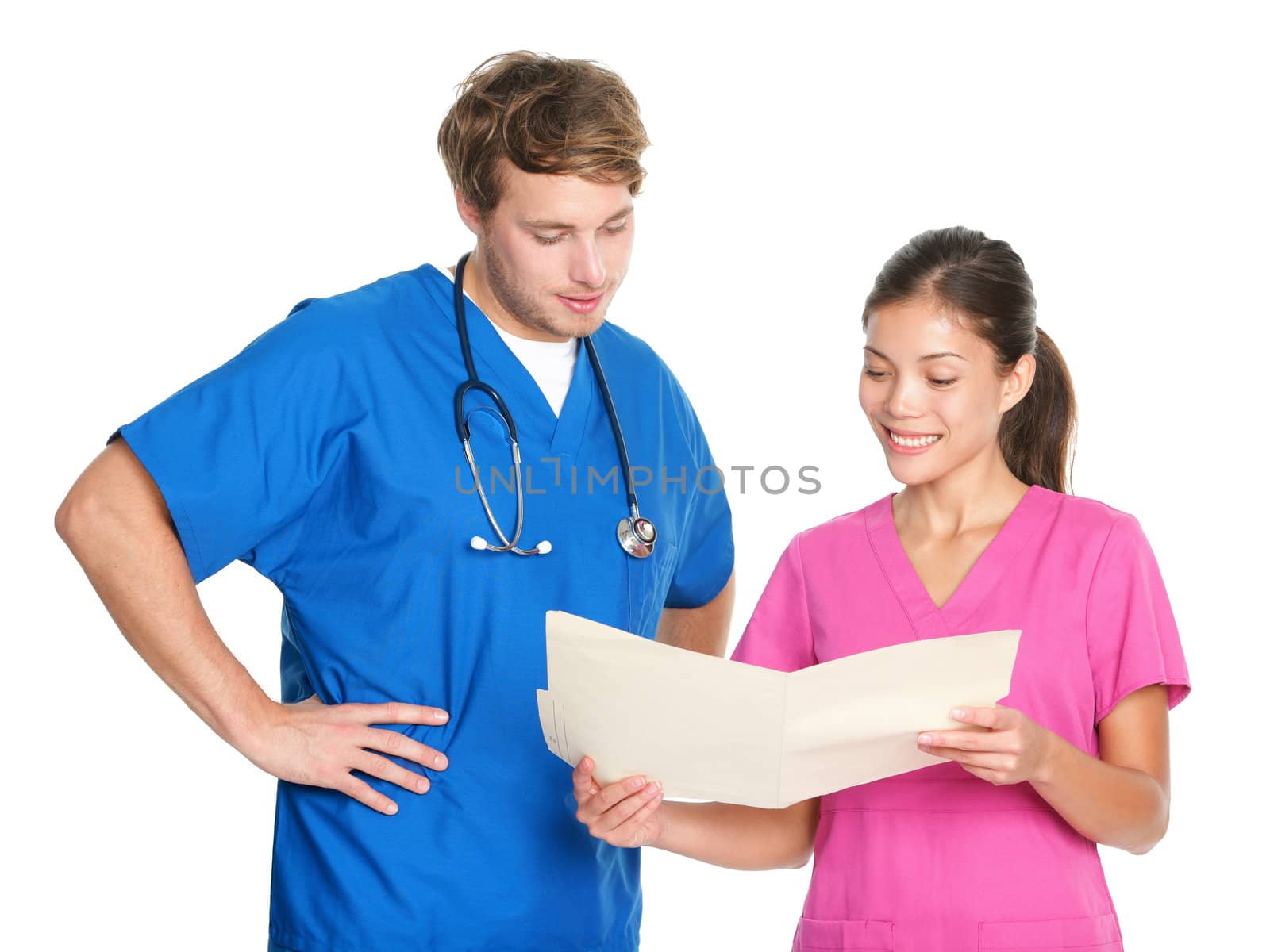 Medical nurses or doctors talking working together in team looking at file folder. Young man and woman medical professionals in scrubs isolated on white background. Asian female and Caucasian male in their twenties.