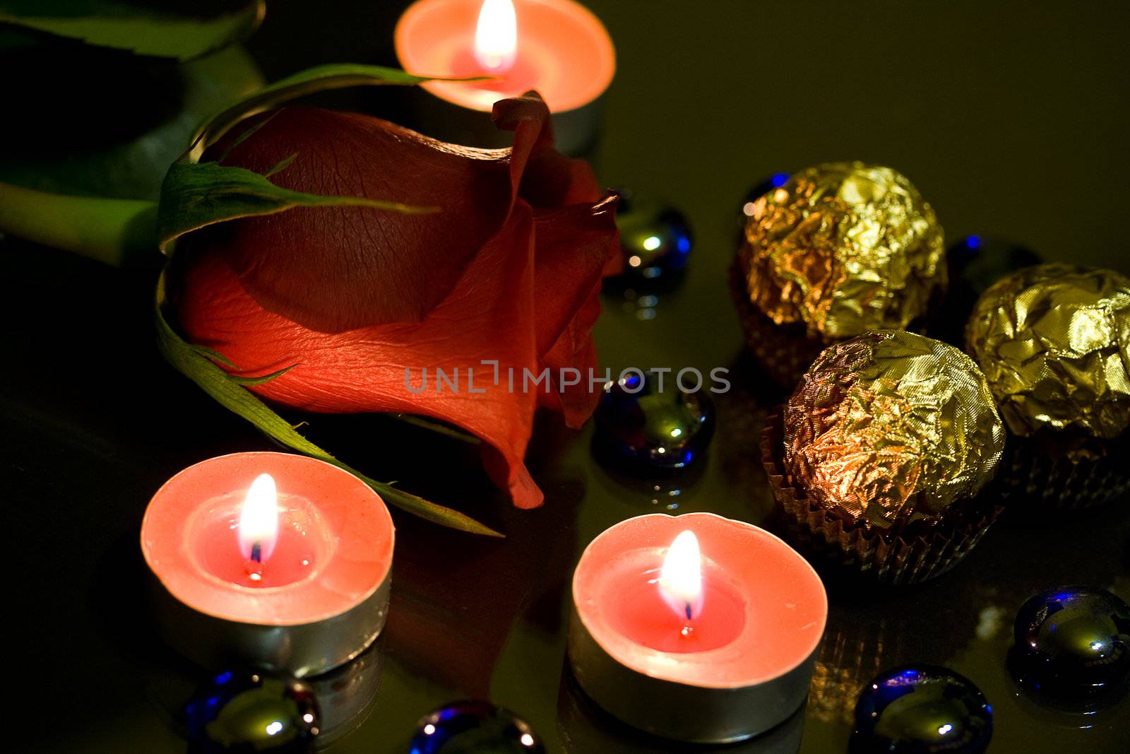 Red roses, candles burning in the night and candy wrapper