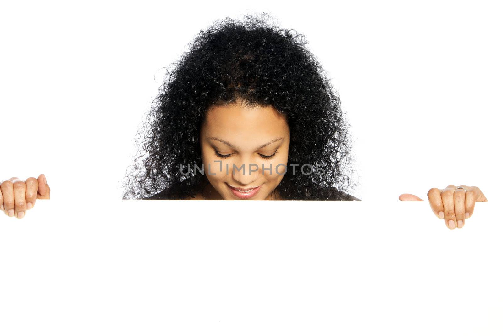 Attractive young African American lady with lovely curly black hair standing looking down at a white blank sign that she is holding in her hands sign that she is holding in her hands