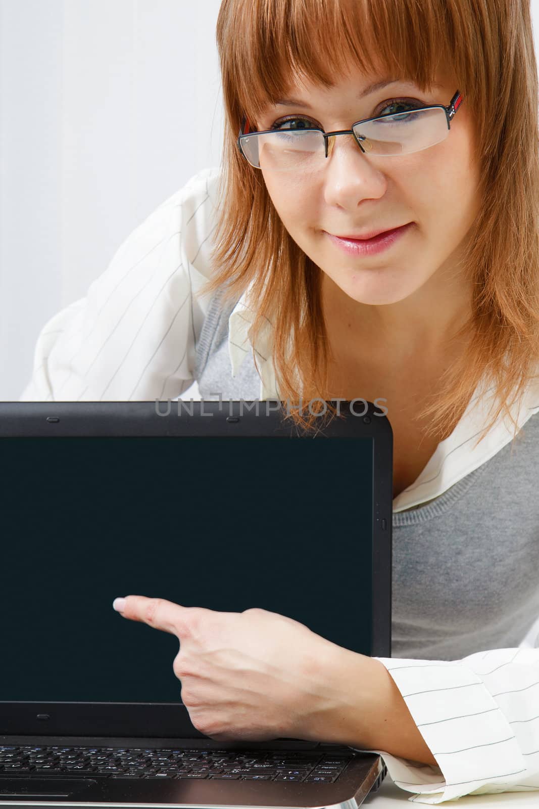 girl with glasses shows a finger on a laptop monitor. Close-up