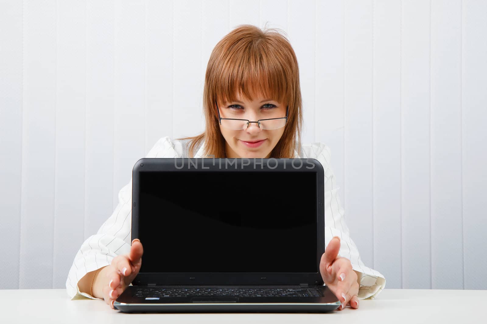 Attractive girl in glasses with a laptop in the office
