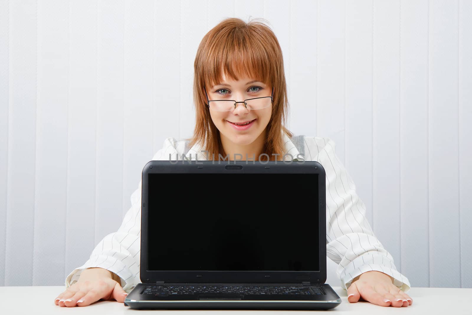 Attractive girl in glasses with a laptop in the office
