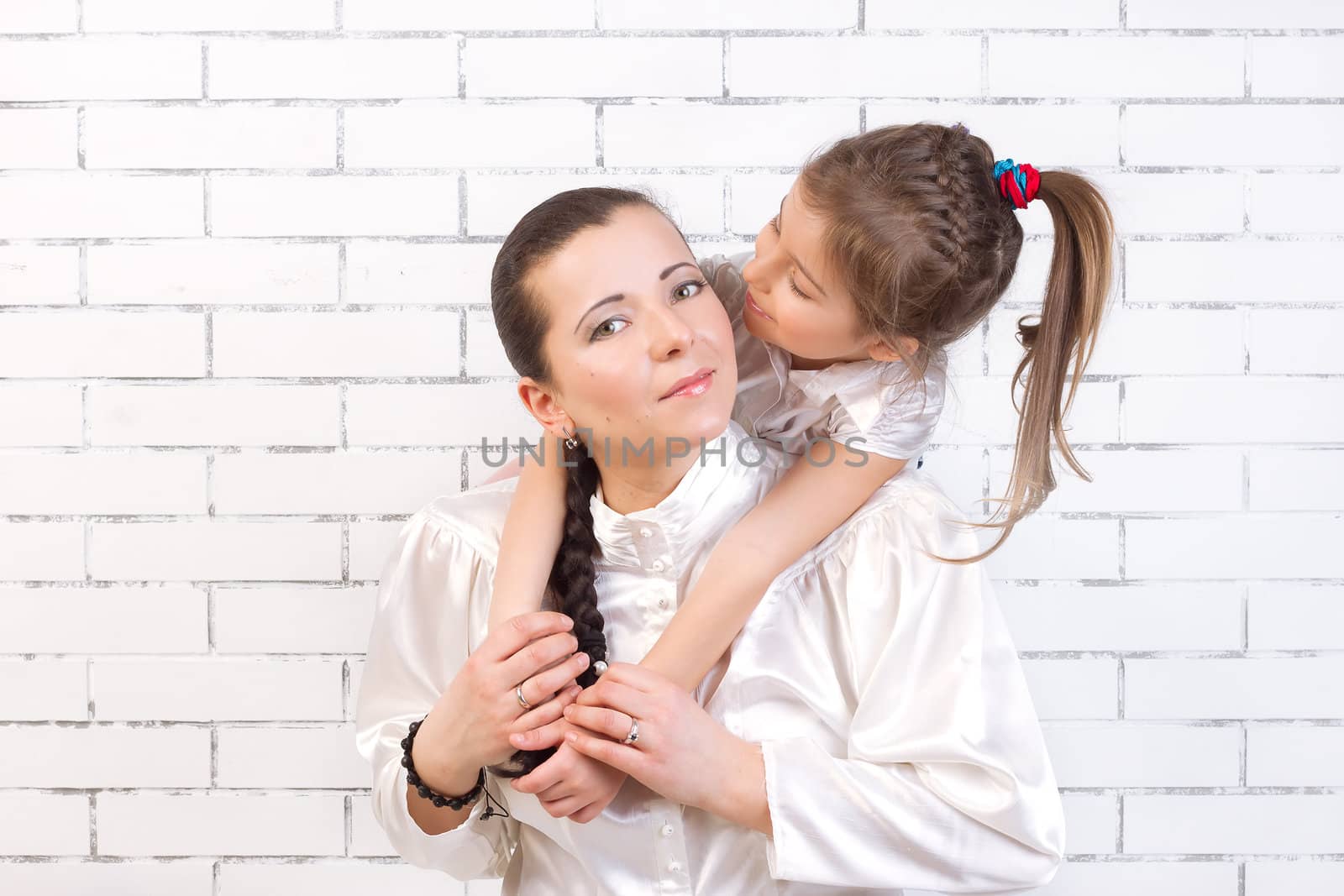 5 year old daughter in a white dress kissing his mother