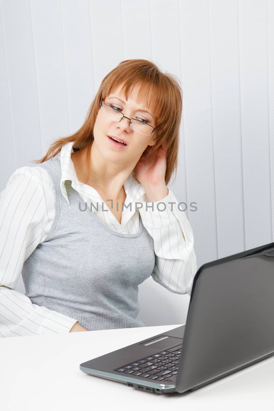 tired girl with a laptop stretches in the workplace