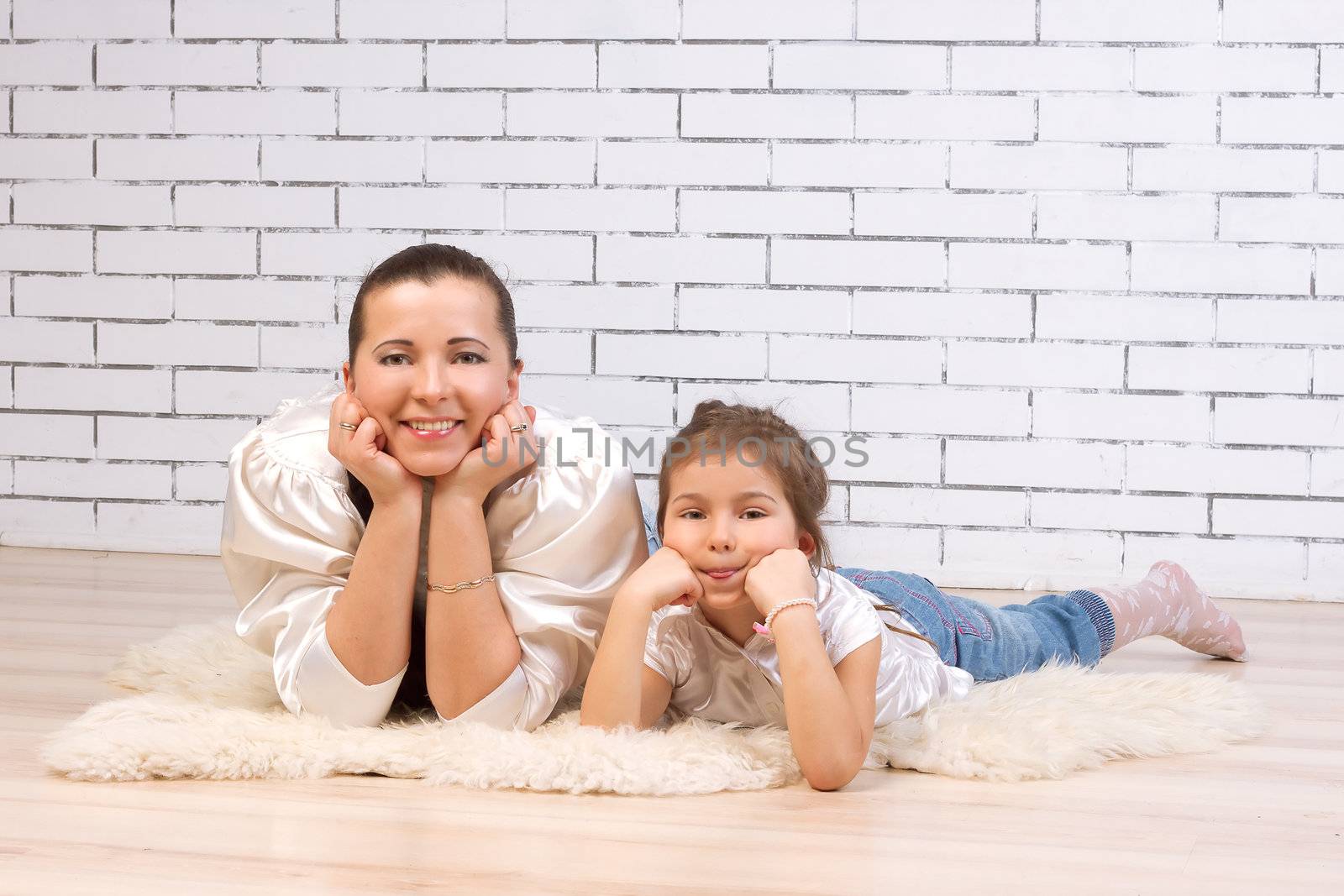 Mother and 5-year-old daughter lying on the floor resting his face with his fists
