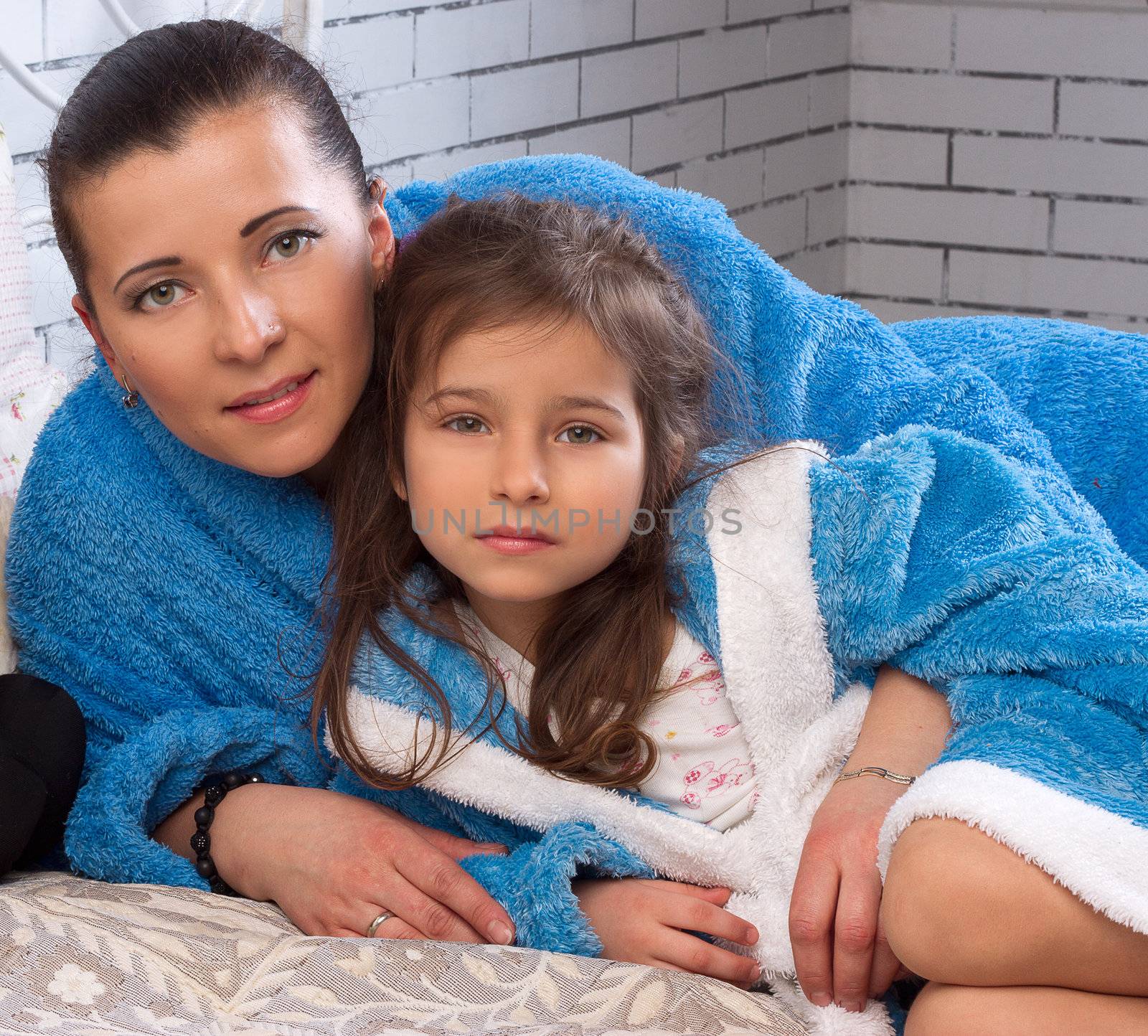 Mom and daughter in blue terry robes on the bed