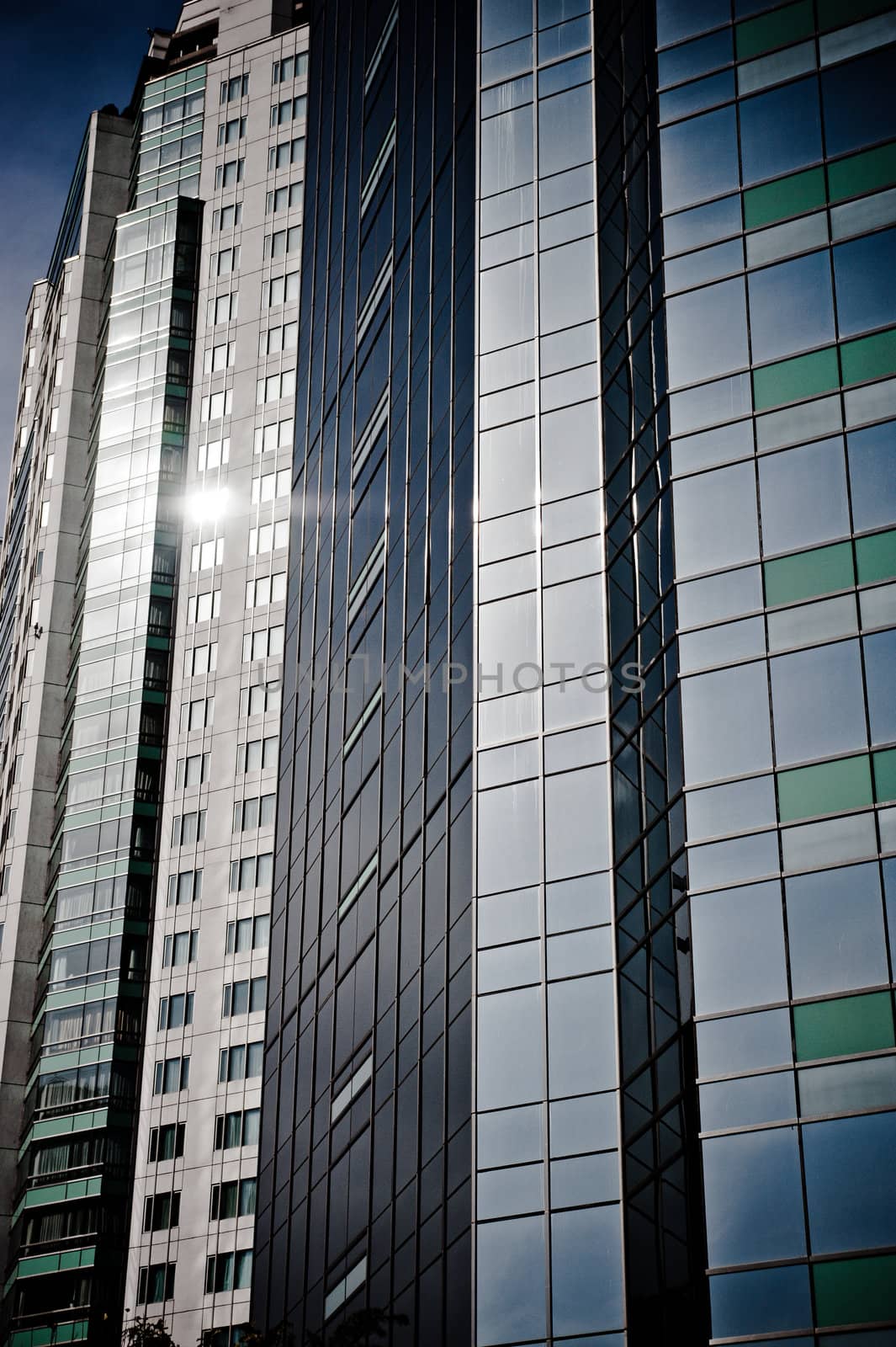 Windows on a group of skyscrapers with reflections of the sun.
