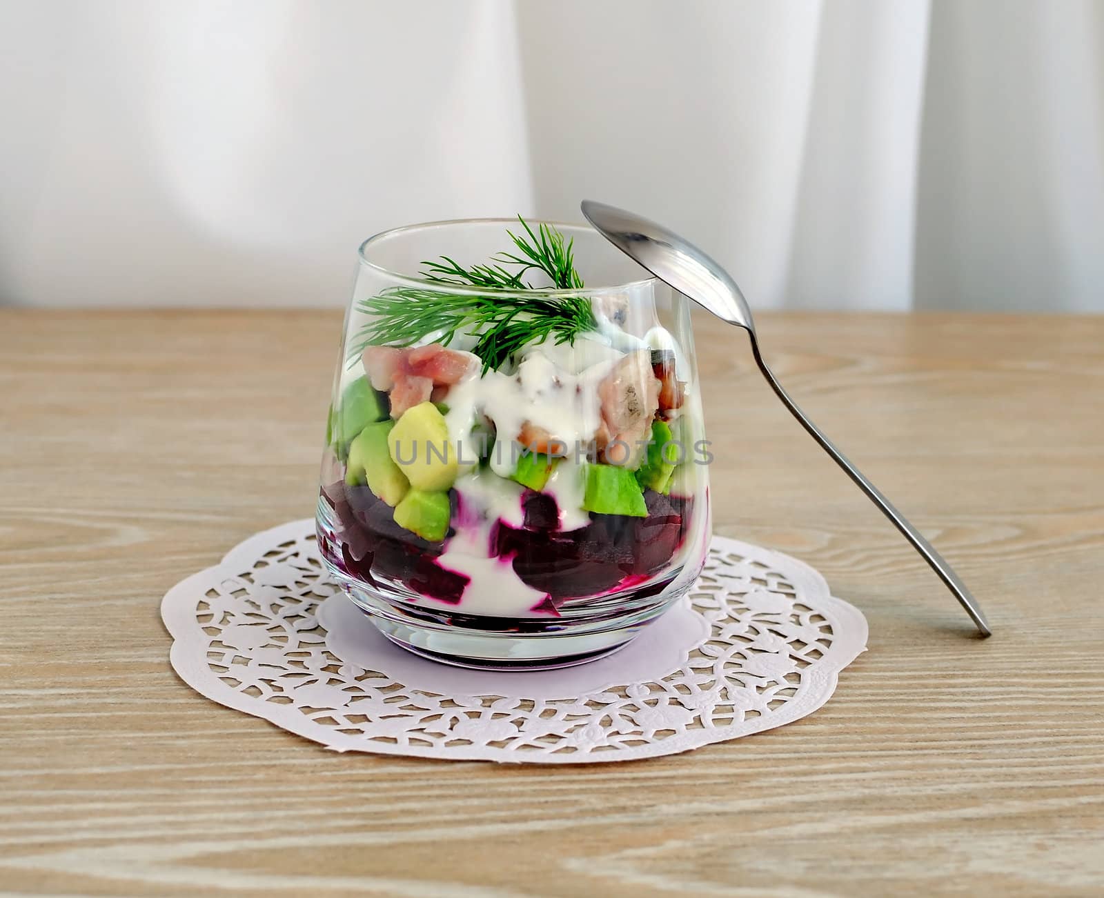 Beetroot salad with avocado and herring in cream sauce in a glass