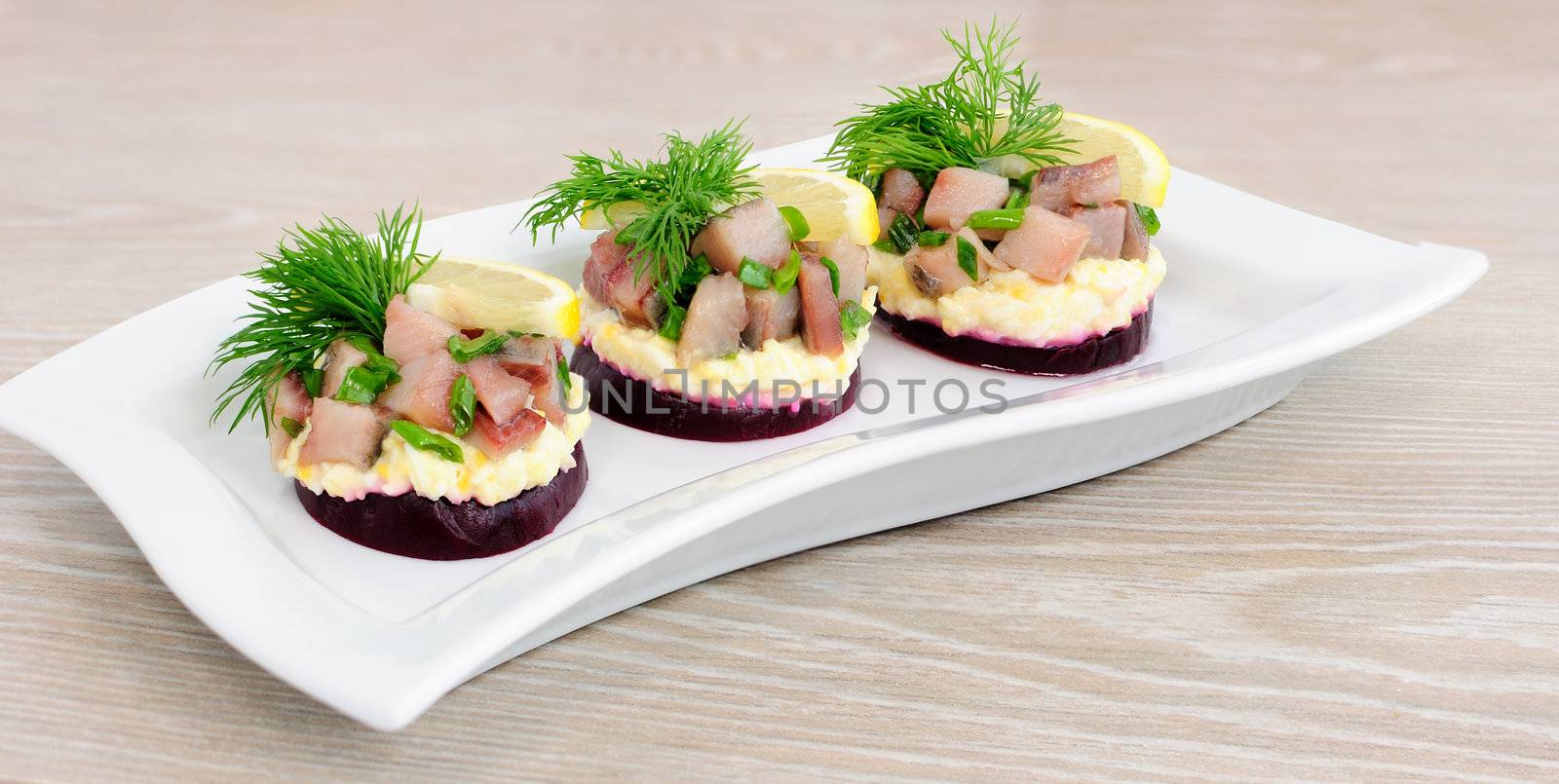 Appetizer of herring with onions on the beets and eggs, lemon and dill