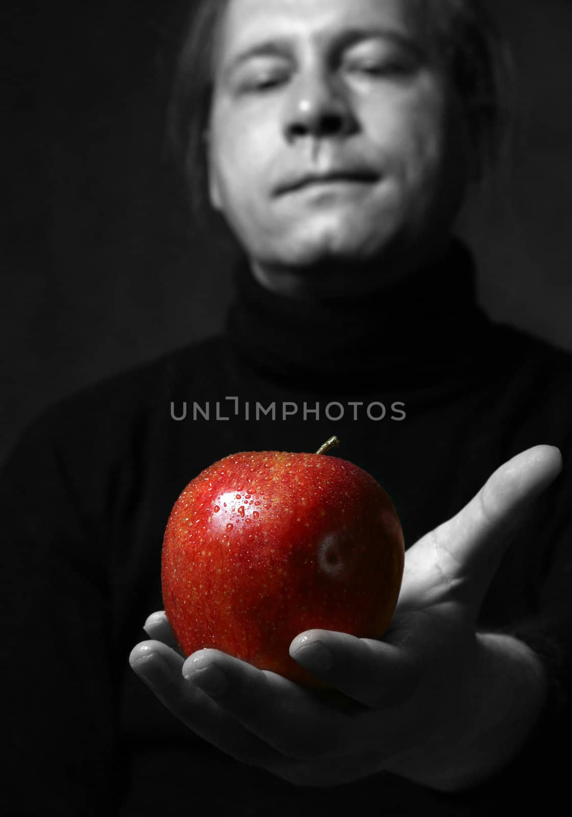 Man's hand with a red apple on a dark background