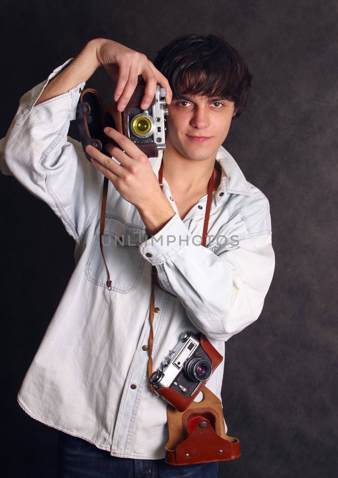 Portrait of smiling young man with two old cameras