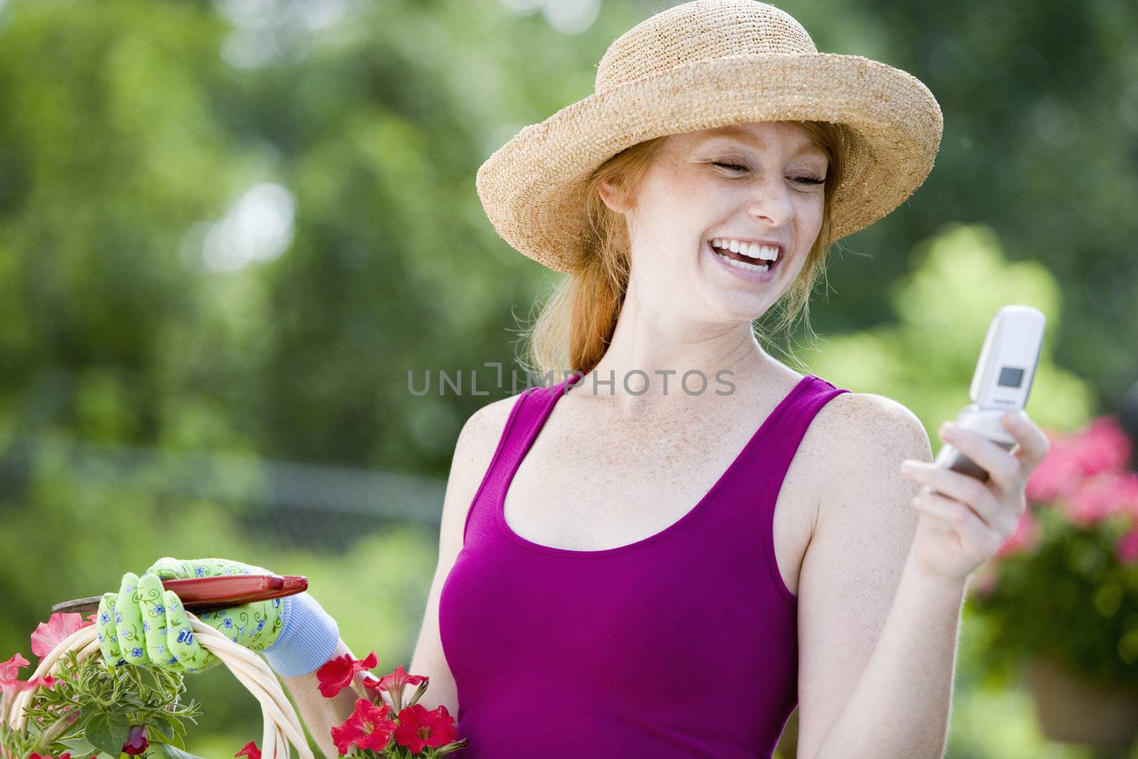 Laughing woman gardener looking at her cell phone