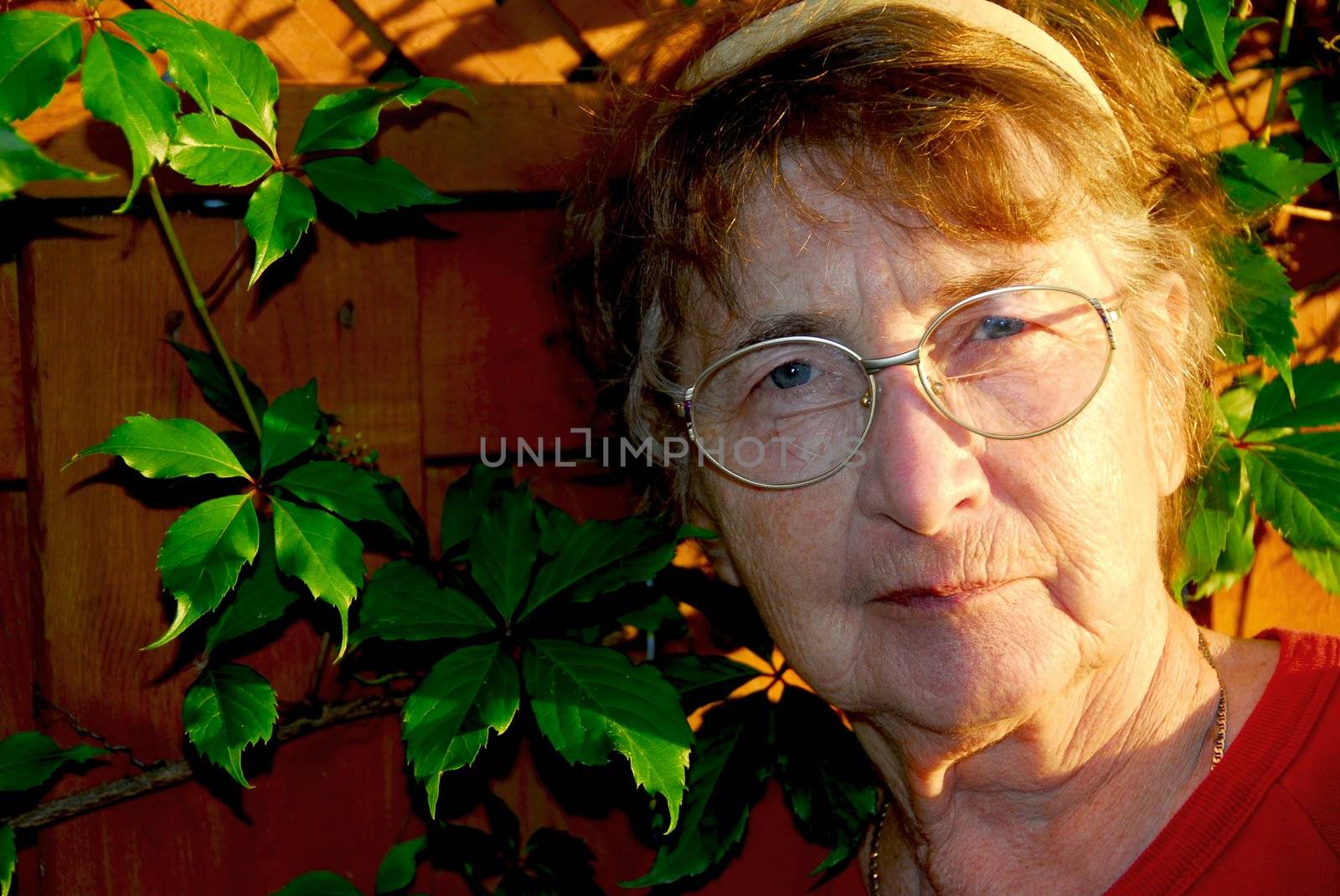 Portrait of an elderly woman outside with green vines