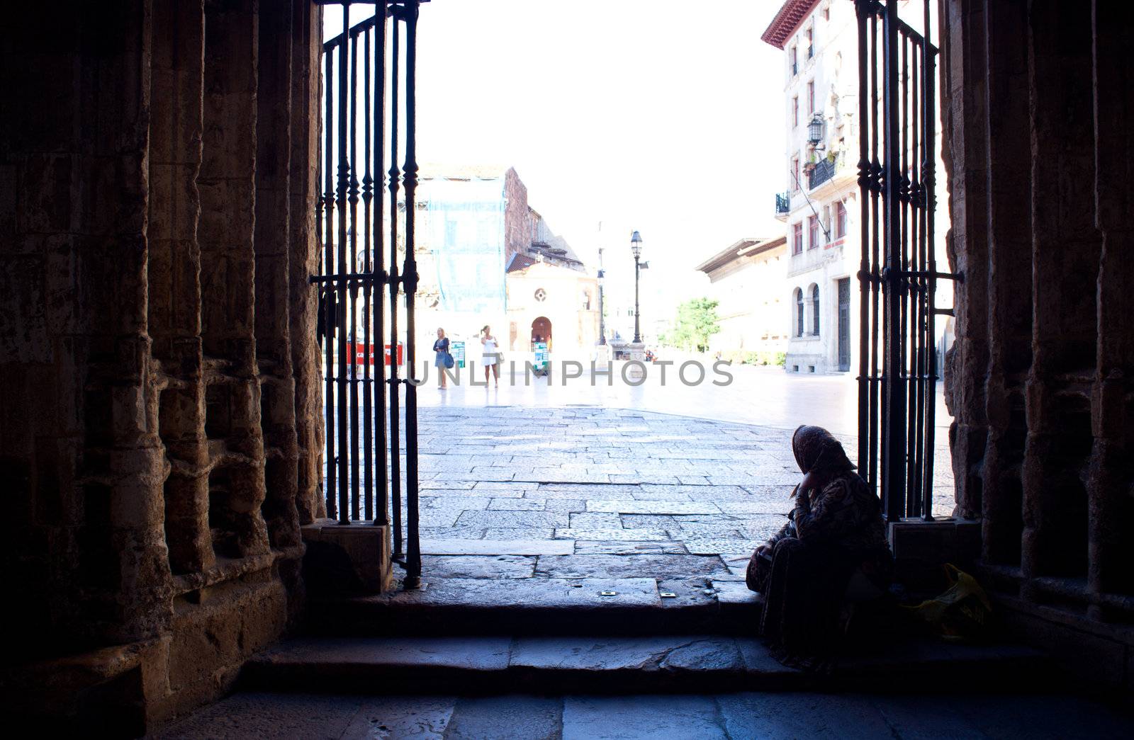An old beggar next to the door of the church