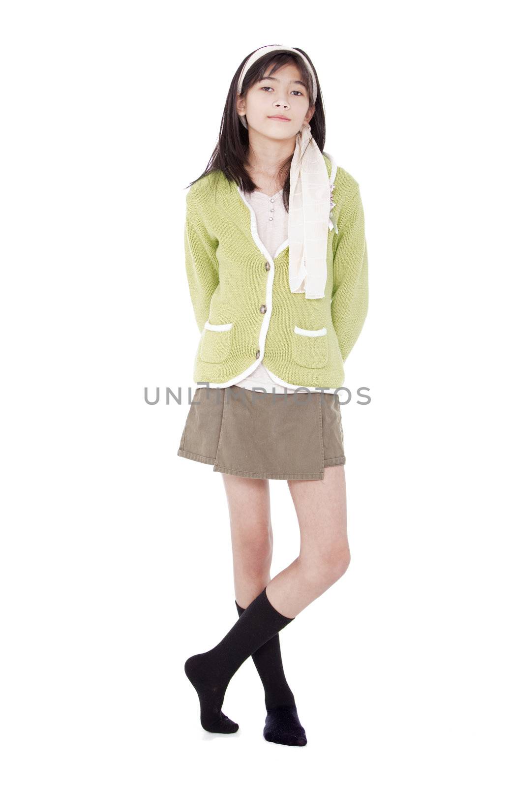 Unsmiling confident young biracial asian girl in green sweater standing, isolated