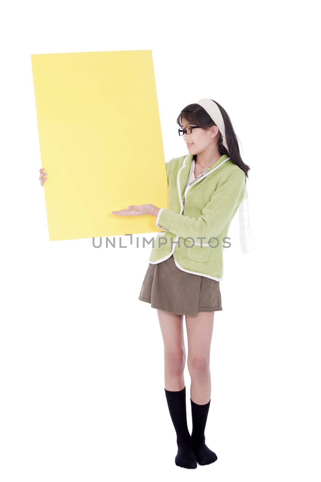 Cute biracial asian girl in green sweater and glasses gesturing to a blank yellow sign, isolated