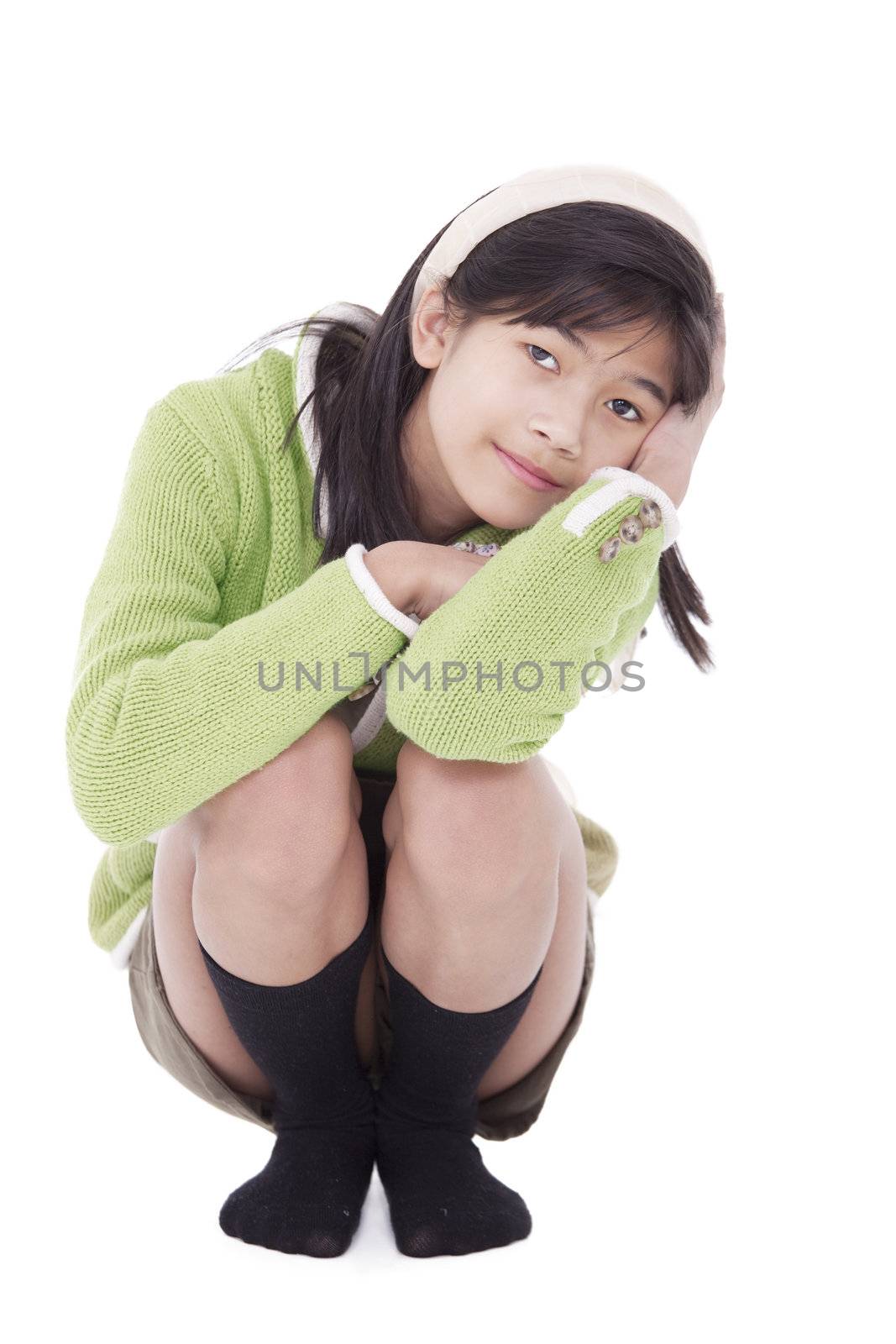 Little biracial asian girl kneeling down, resting. Lime green sweater