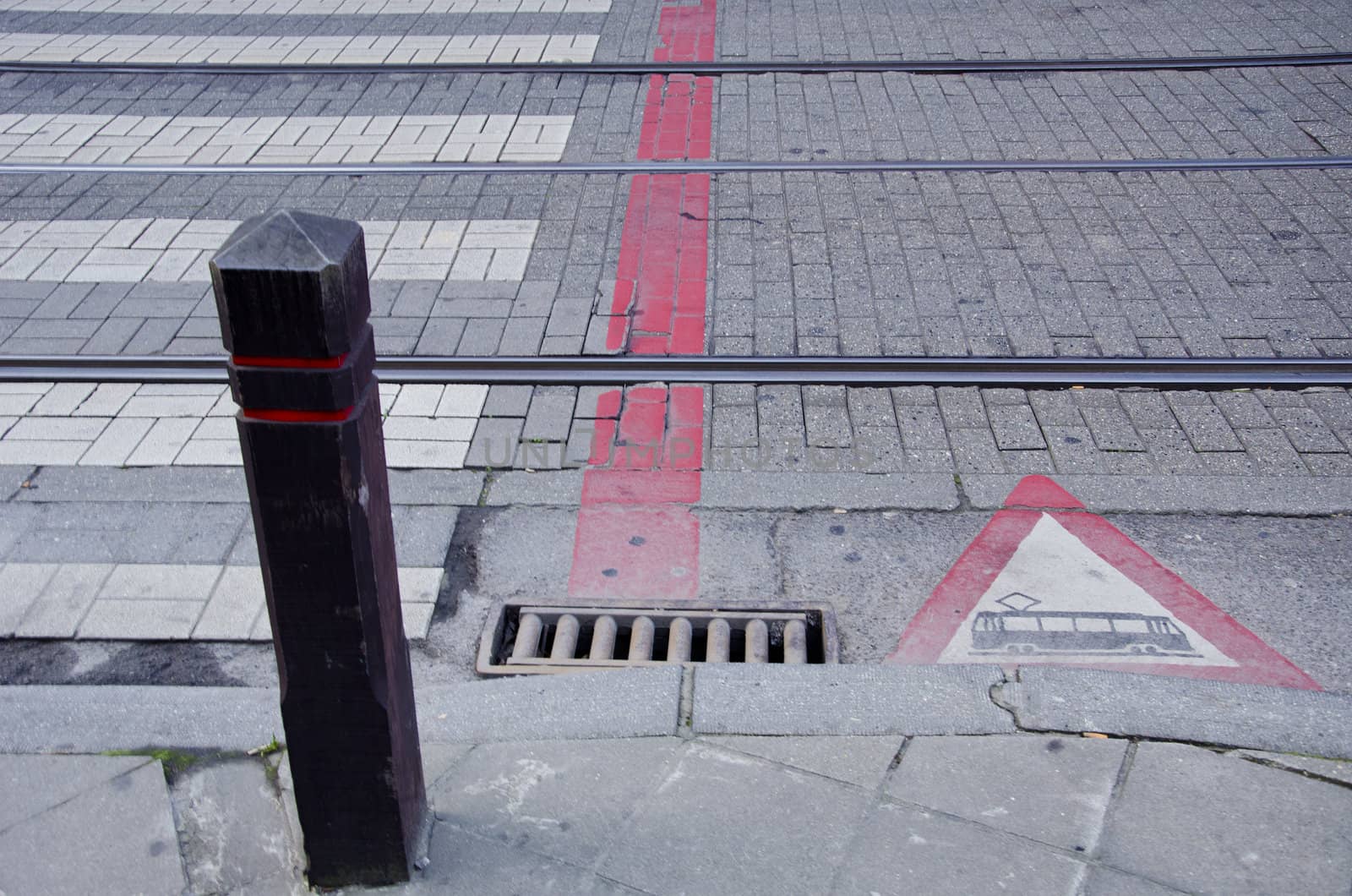 Sidewalk and tram rails. Warning sign. Fragment of street. Passenger transportation.