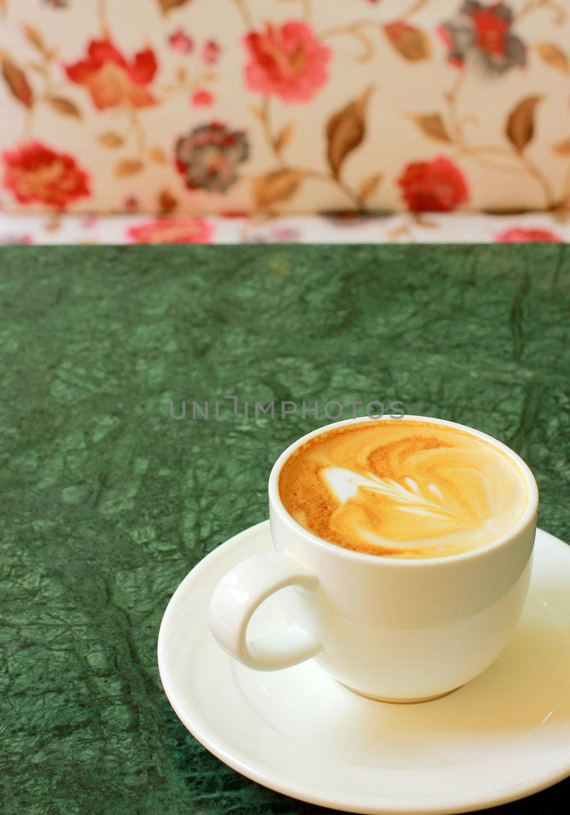 Cappuccino or latte coffee on table with flower chair