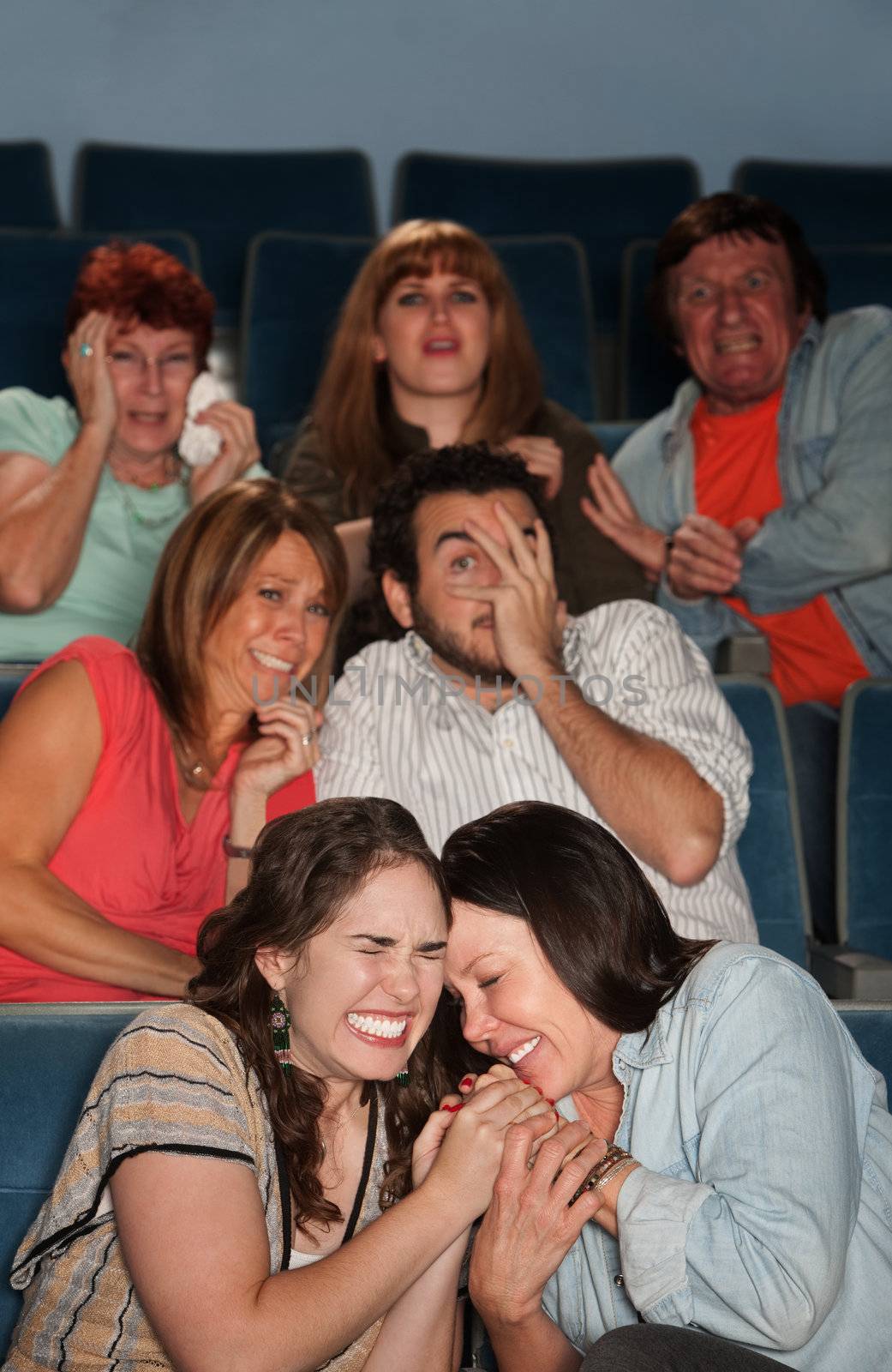 Group of scared people watch horror movie in theater
