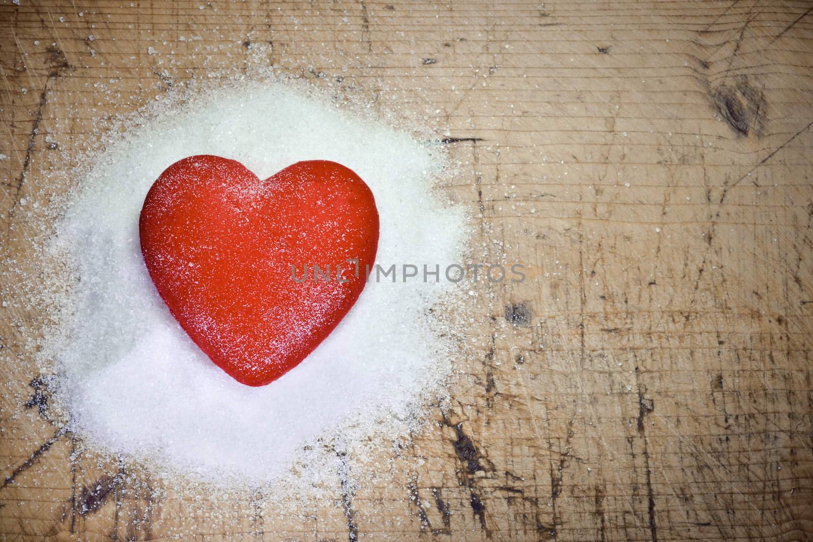 Read heart sitting on sugar on wood background