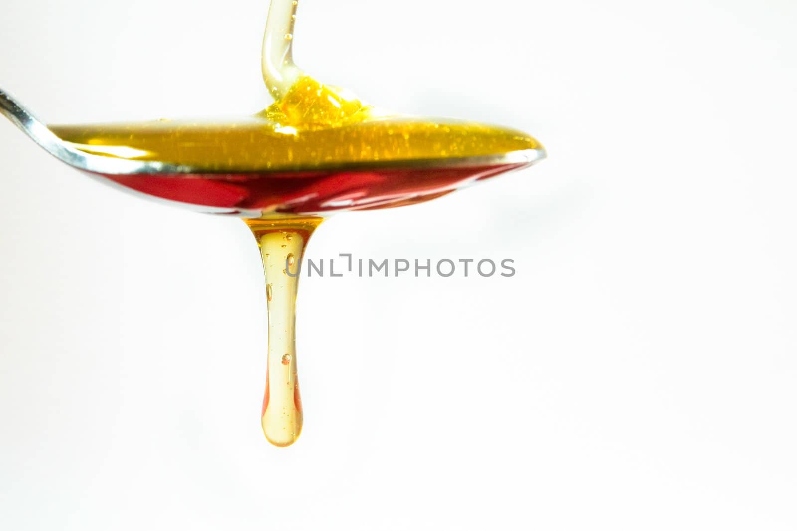 honey in a spoon on white background by chrisroll