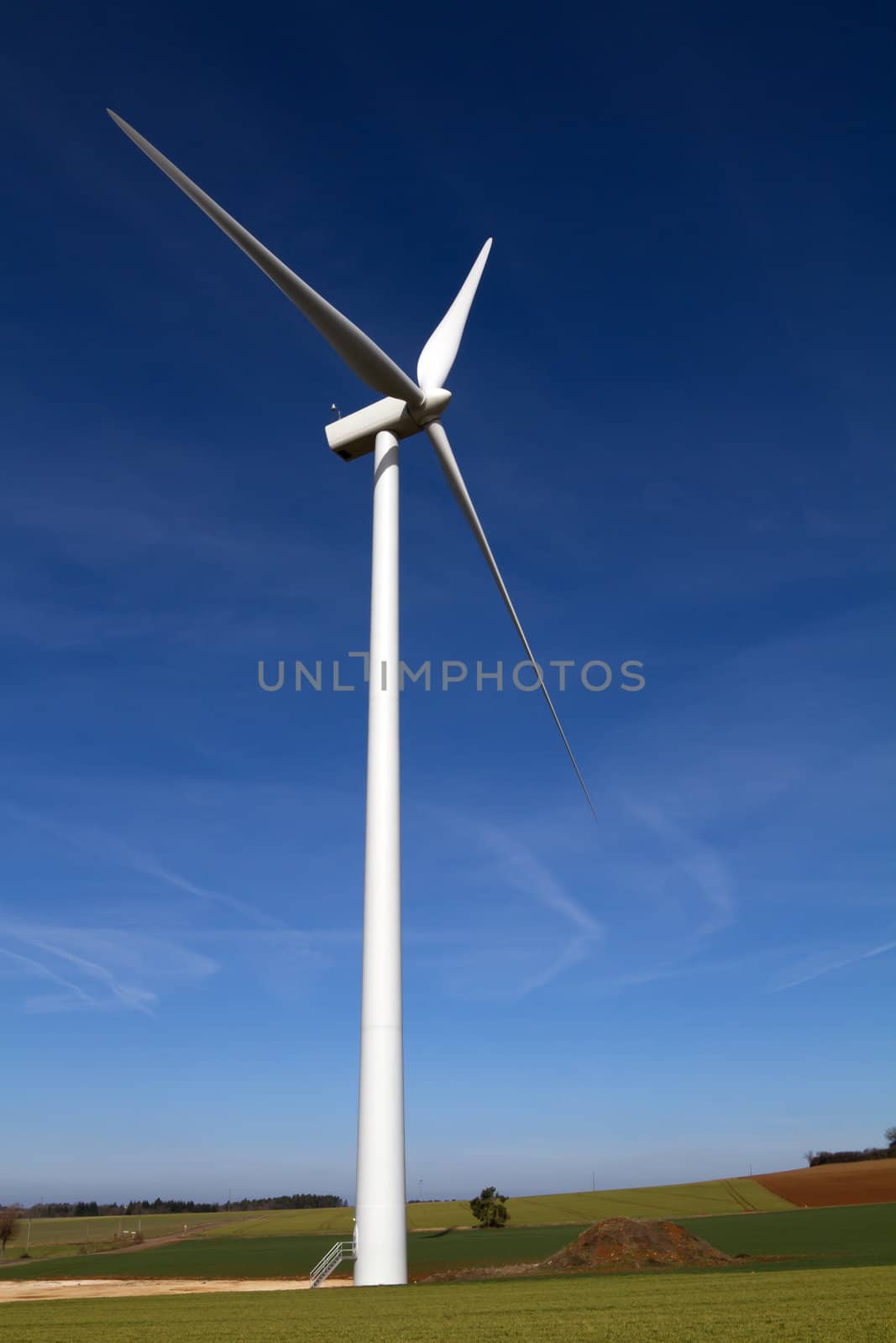 Wind turbine on blue sky by chrisroll