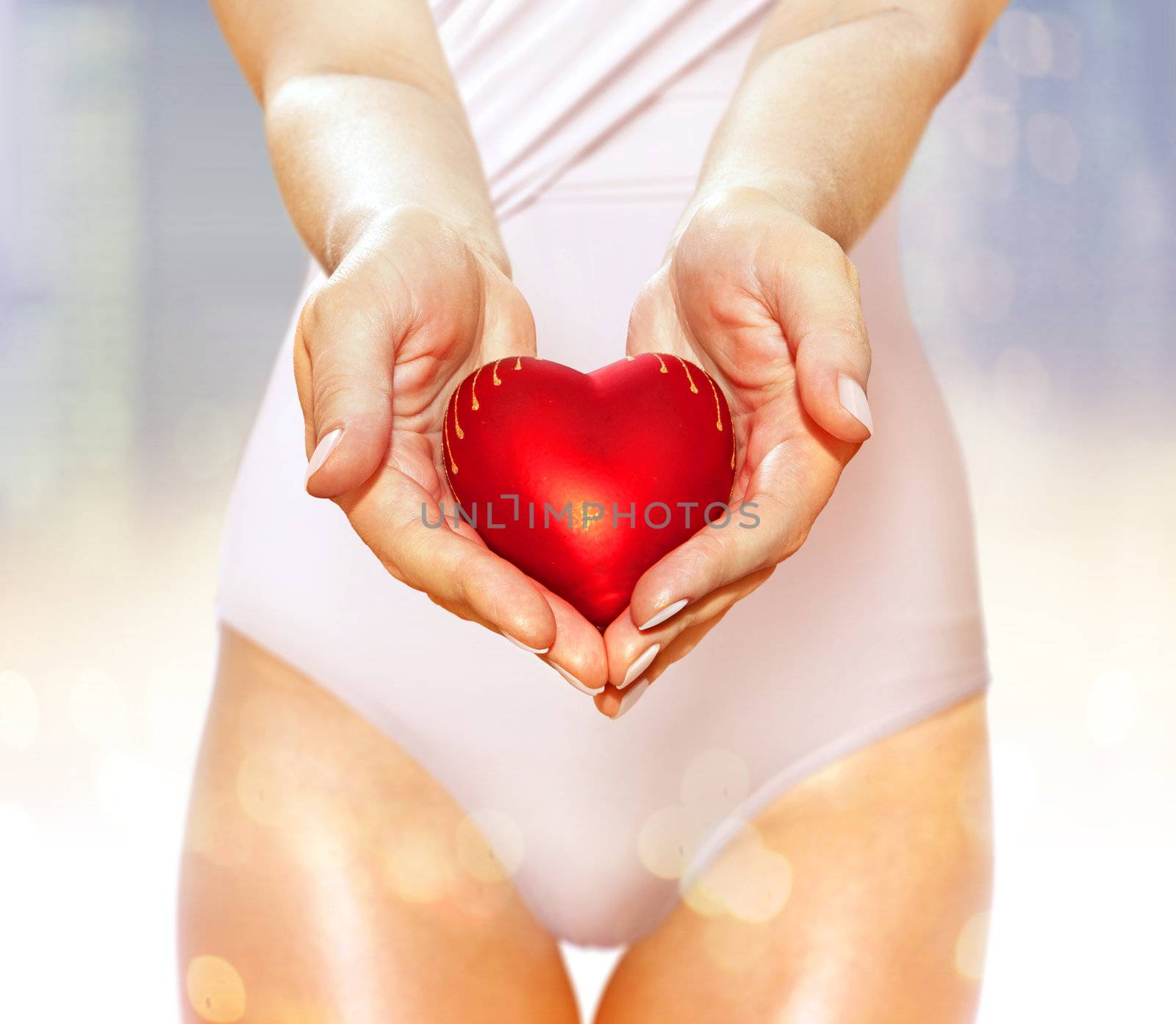 artificial red heart on hands of beautiful woman