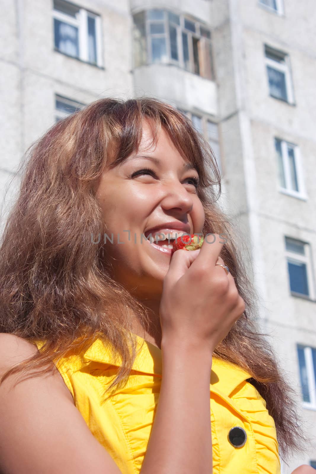 Young beautifull woman holds in hand one ripe strawberry and prepares to eating it