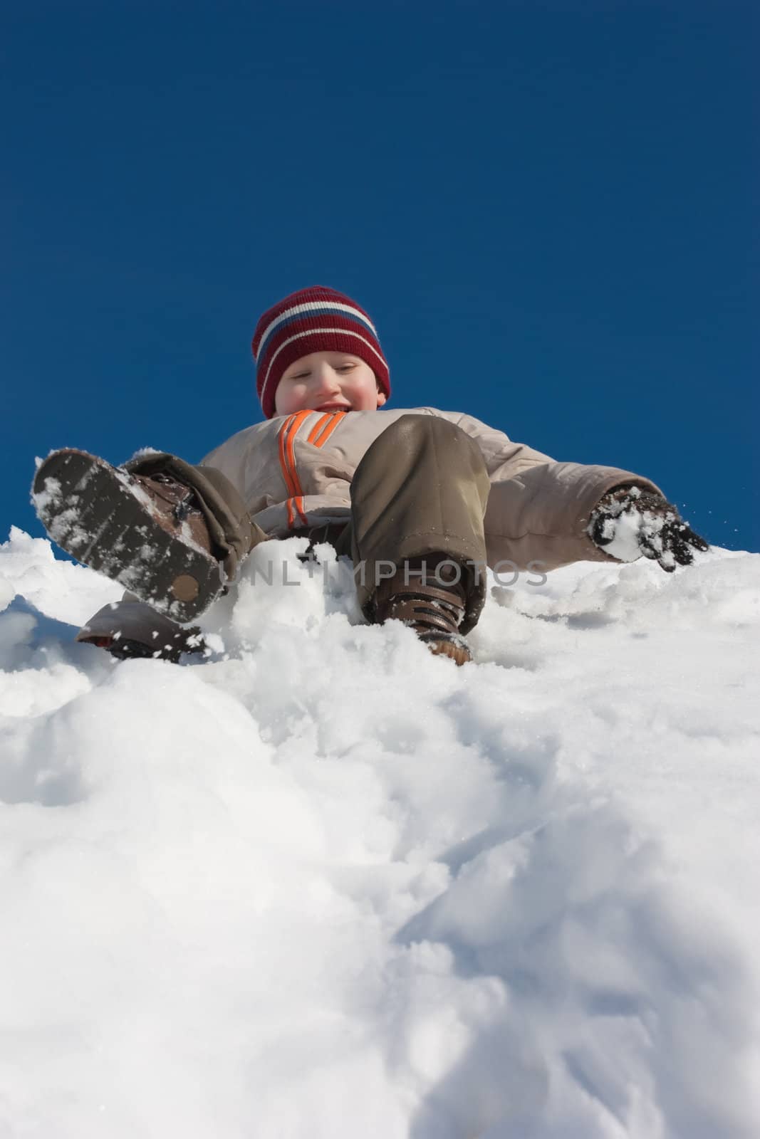 The boy moves down from an ice slope and laughs