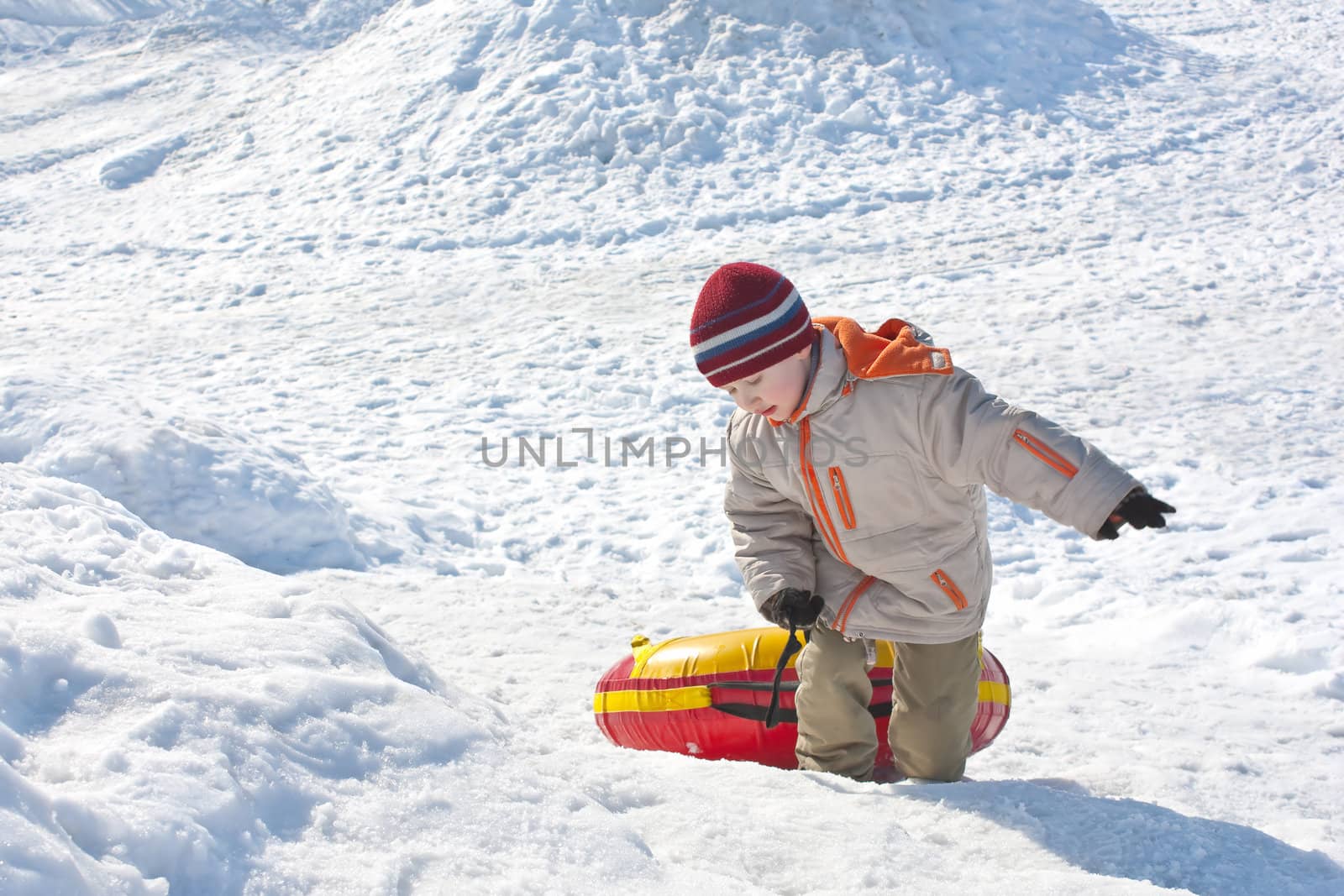 Boy drags red-yellow tube on a snow