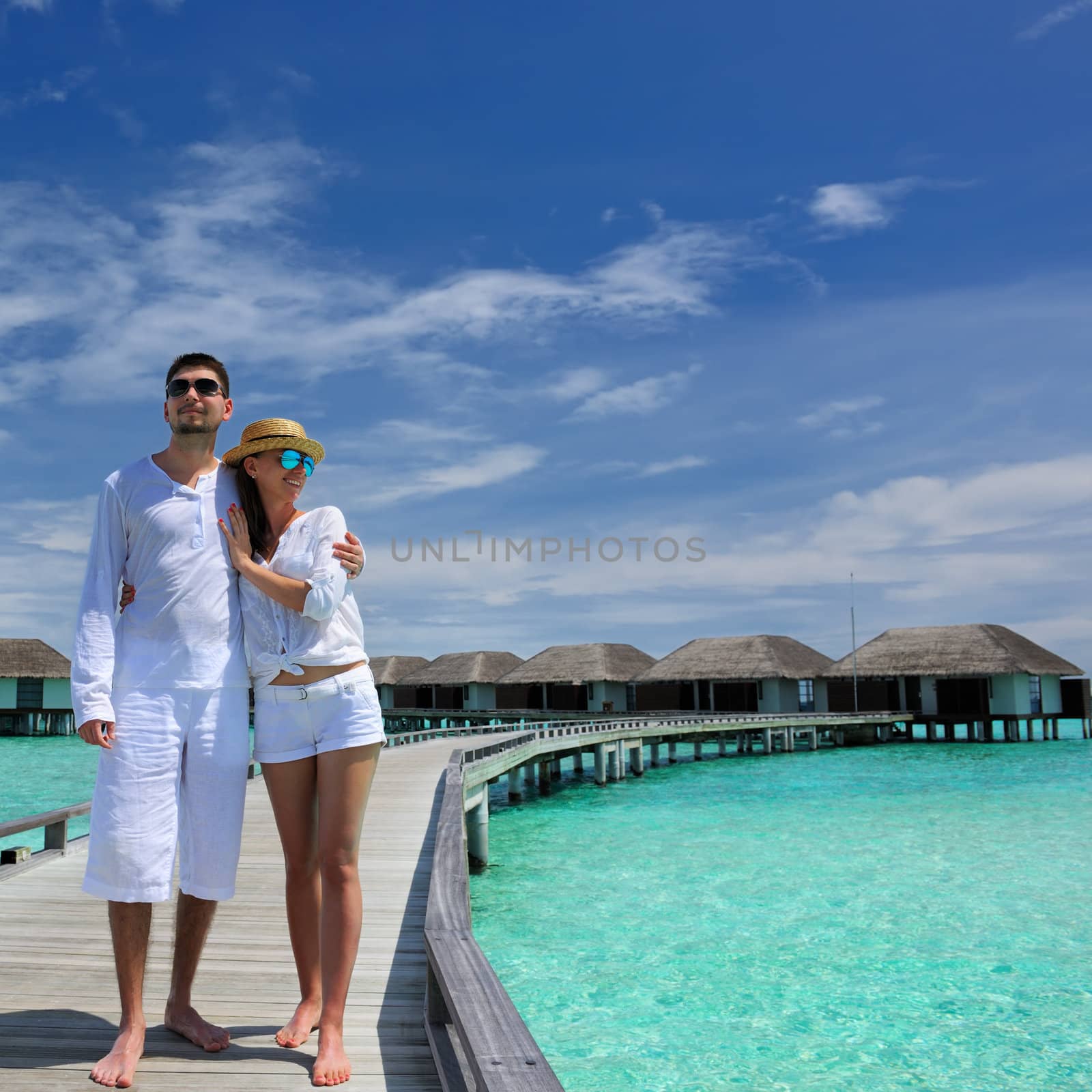 Couple on a tropical beach jetty at Maldives