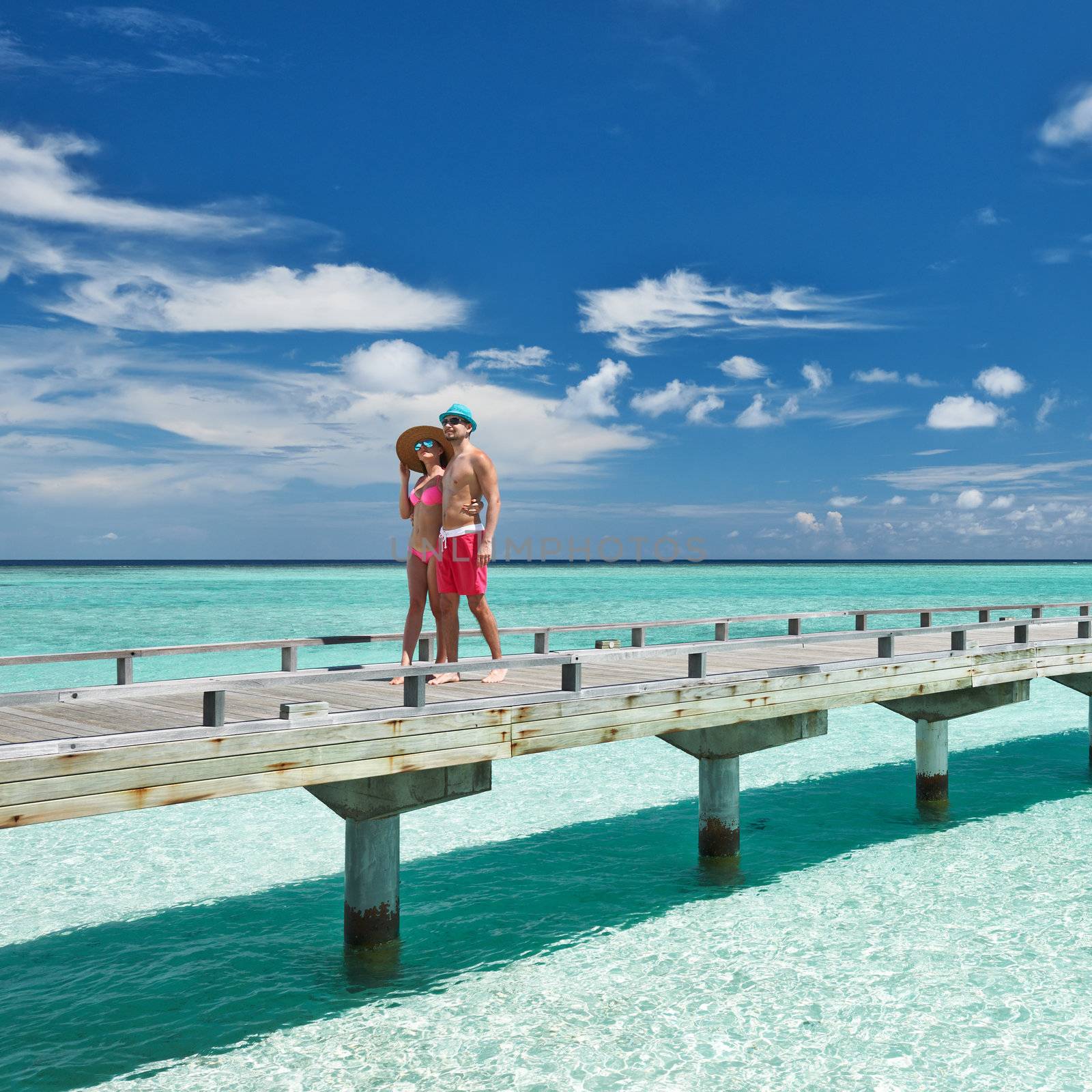 Couple on a beach jetty at Maldives by haveseen