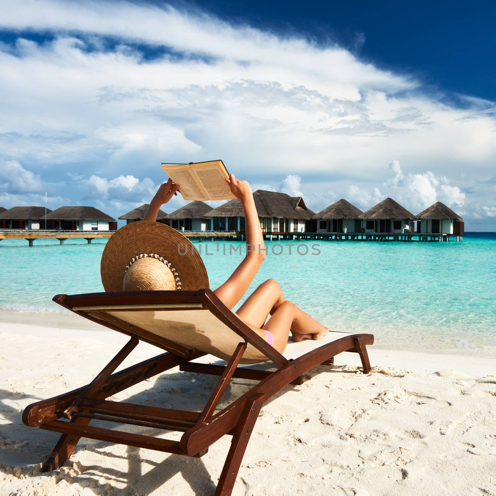 Young woman reading a book at beach by haveseen