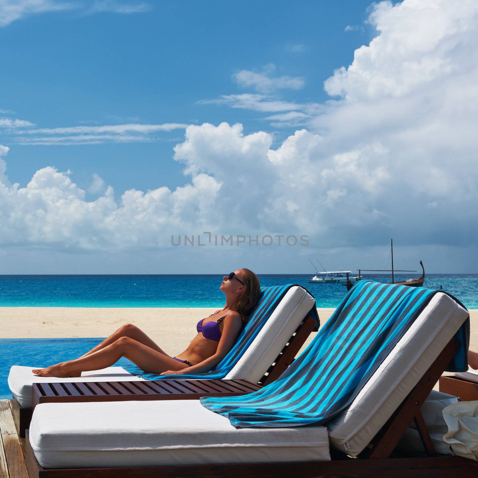 Woman relaxing in chaise lounge at the poolside 