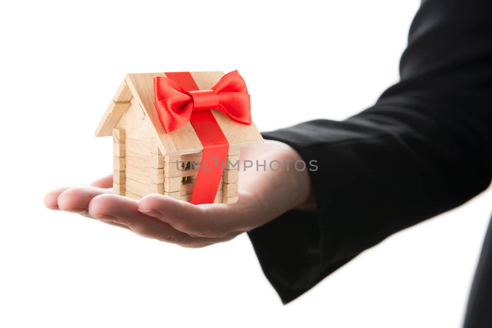Small wooden house with red bow in a hand