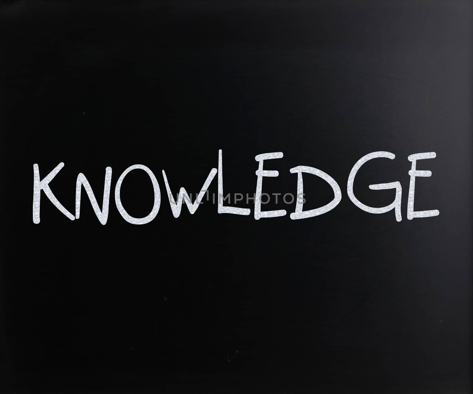"Knowledge" handwritten with white chalk on a blackboard