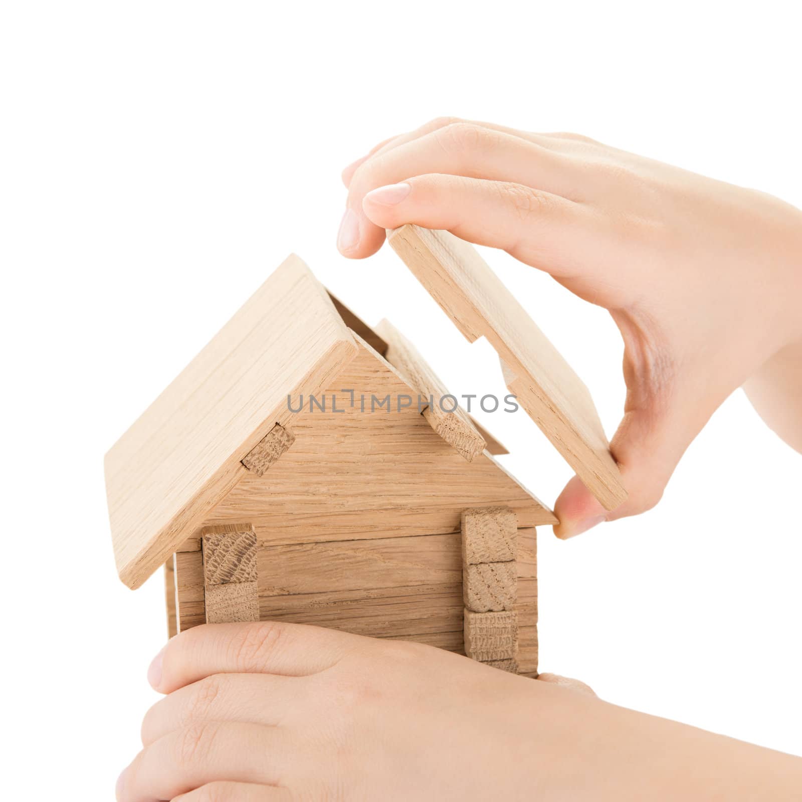 Child hands build a wooden house