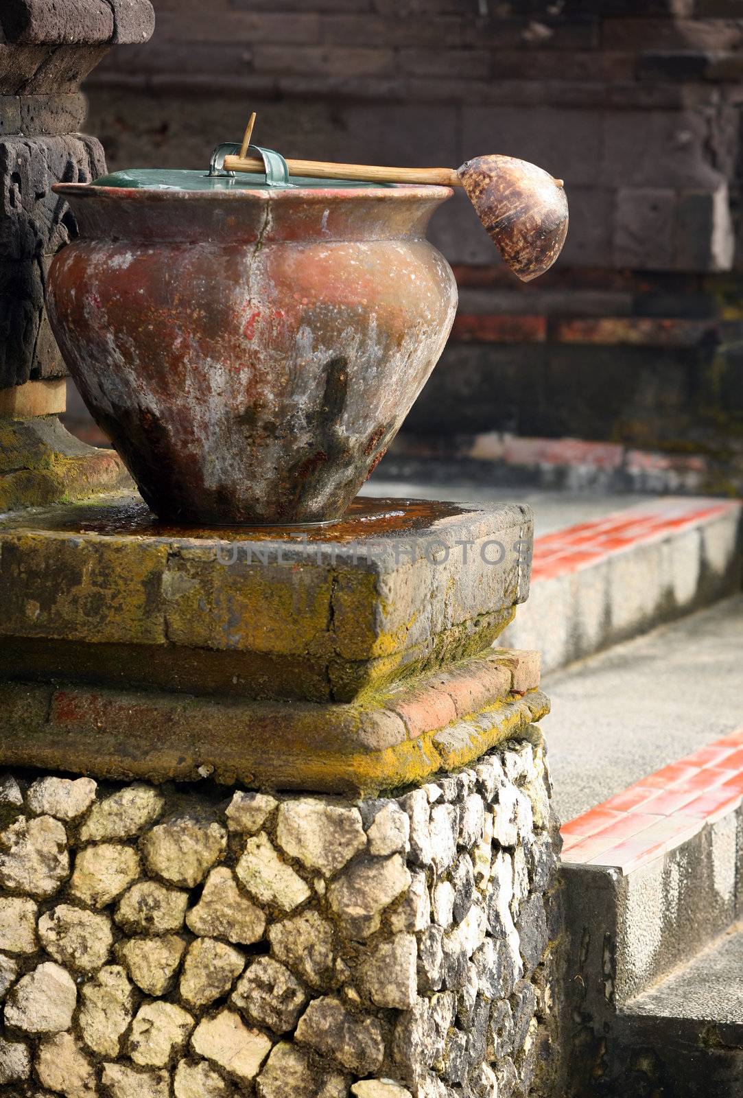 Ancient pot with a ladle before a temple for washing legs. Indonesia. Bali