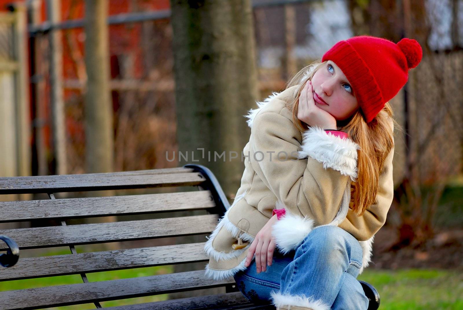 Portrait of a young girl sitting on a bench outside