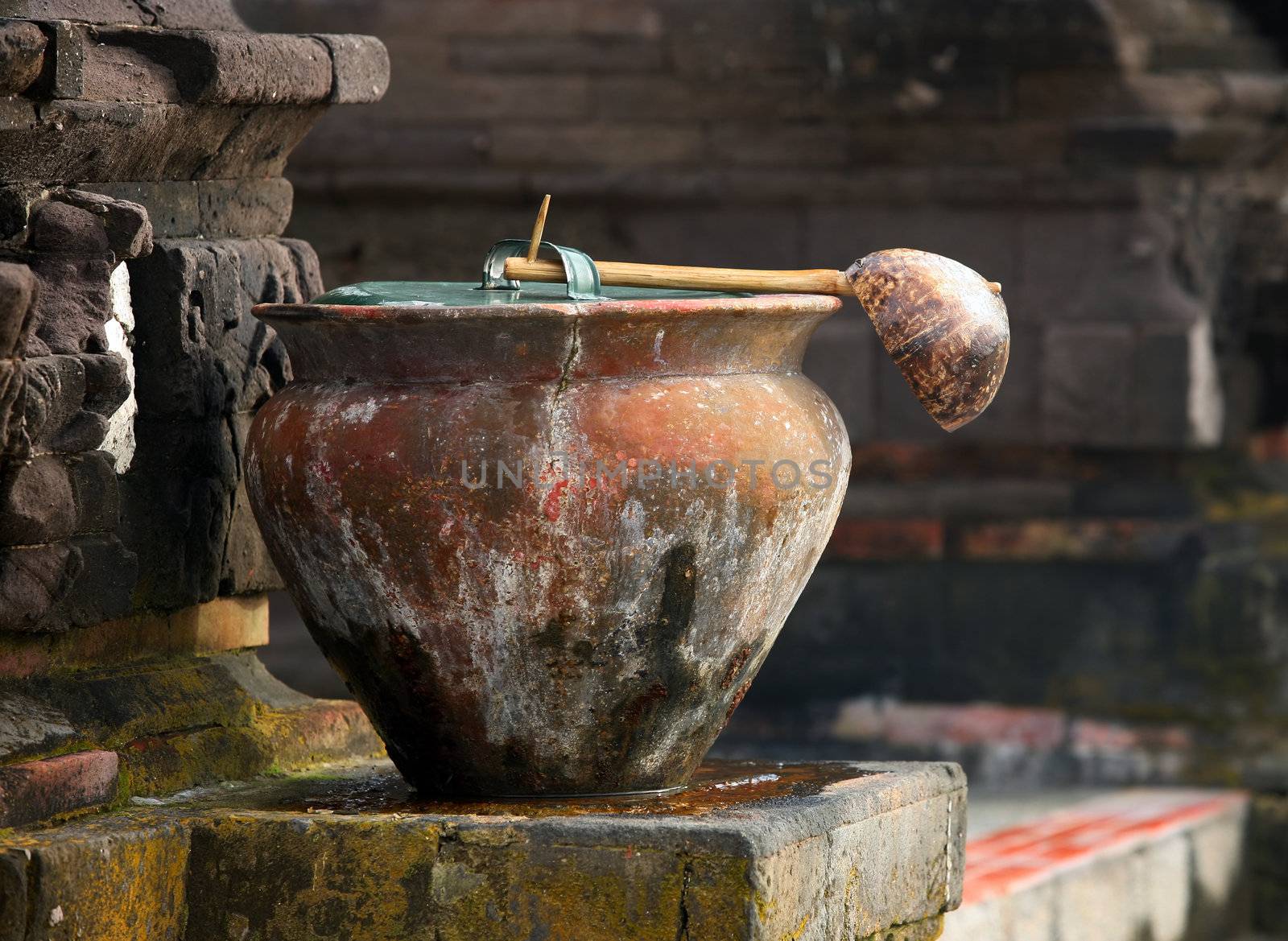 Ancient pot with a ladle before a temple for washing legs. Indonesia. Bali