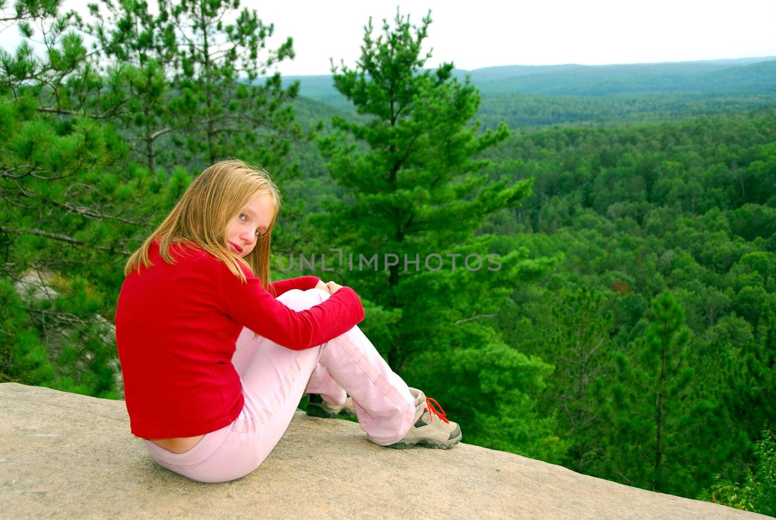 Young girl sitting on an edge of a cliff