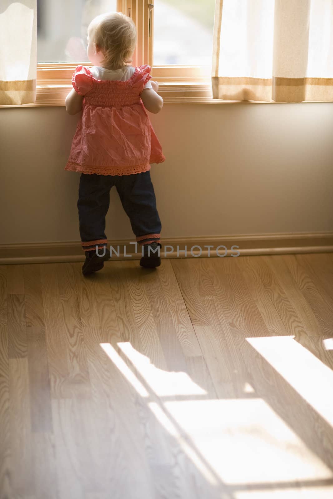 Adorable toddler on Tippy Toes looking out window