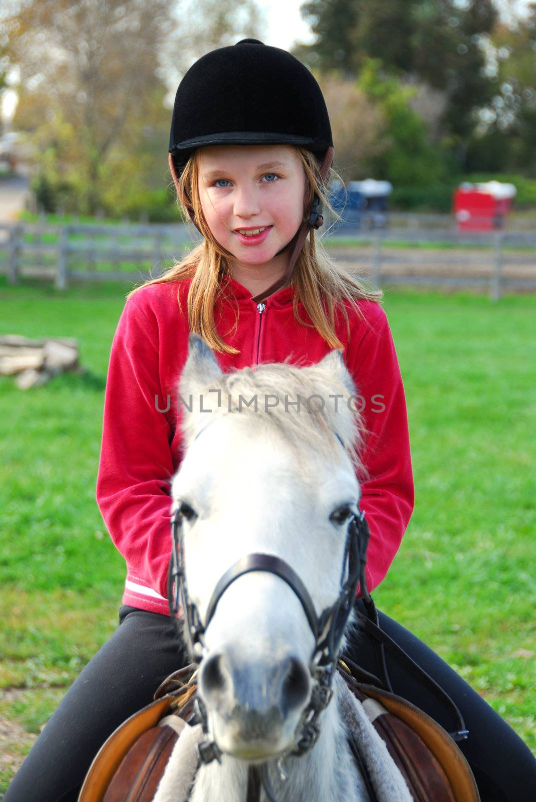 Young girl riding a white pony at countryside