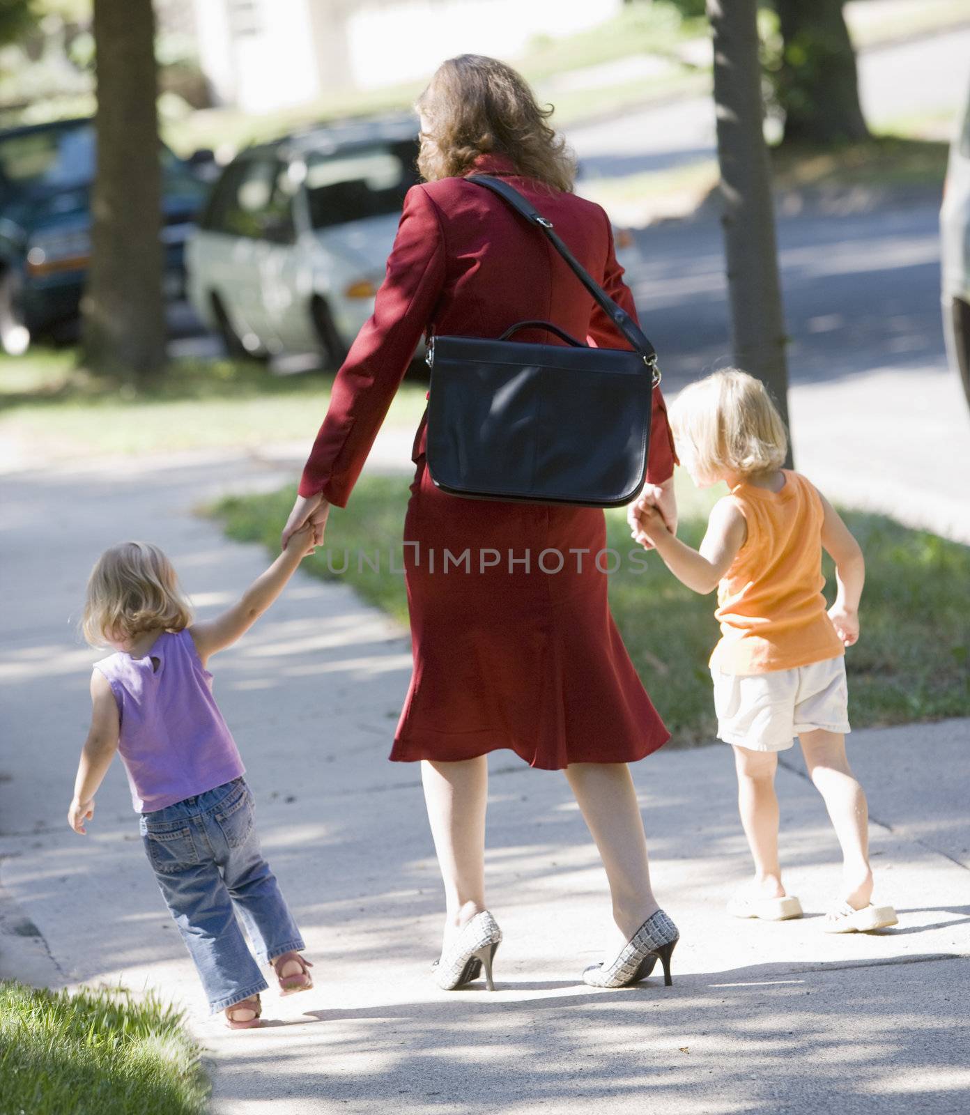 Working mom bringing her kids to daycare by edbockstock
